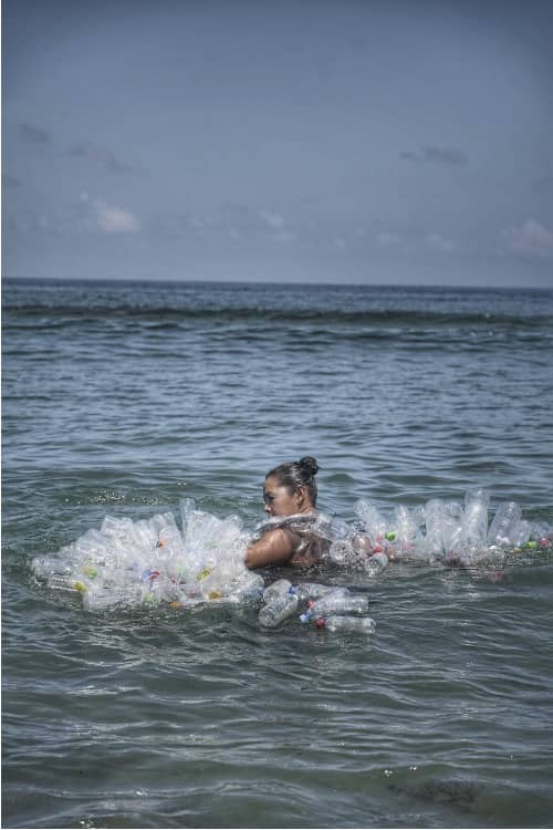 Bari-Bari film still, with a dancer surrounded by plastic bottles in the sea.