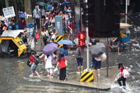 Commuters wade through gutter-deep flood in Manila