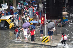 Commuters wade through gutter-deep flood in Manila