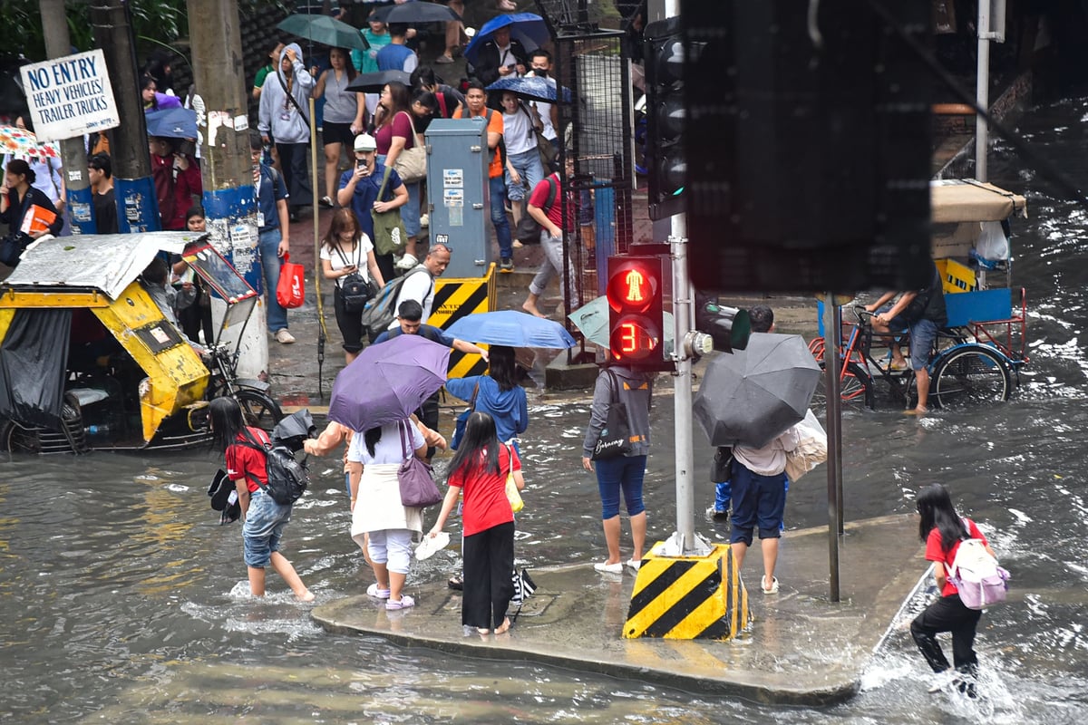 Commuters wade through gutter-deep flood in Manila