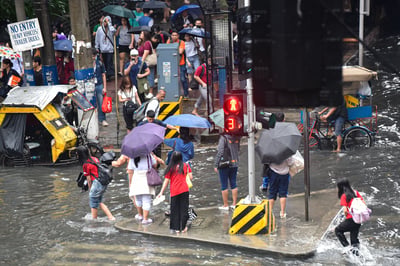 Commuters wade through gutter-deep flood in Manila