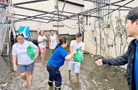 AN SM Foundation volunteer wades through floodwaters to deliver a Kalinga Pack to a family whose community remains submerged weeks after the habagat floods.