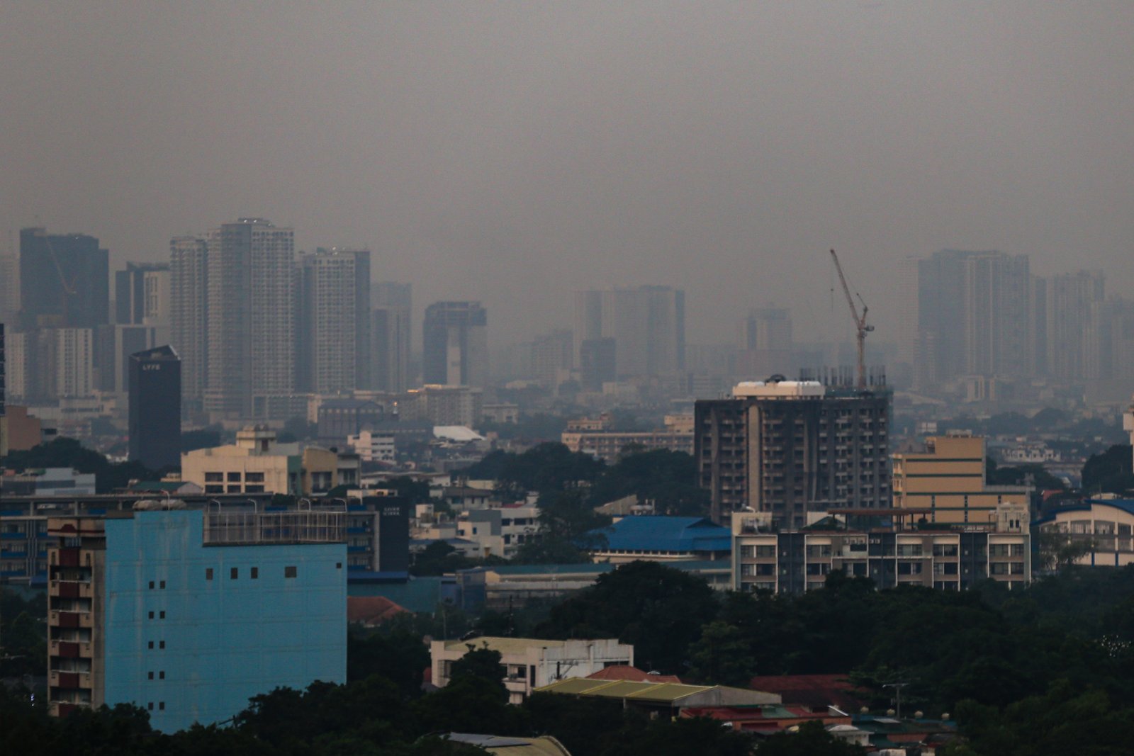 Haze blankets high-rise buildings in Manila, as seen from Quezon City on the morning of 28 September 2026. Air quality in Metro Manila has ranged from moderate to unhealthy levels, with exposure to fine particles potentially aggravating respiratory conditions and causing breathing difficulties. The Department of Environment and Natural Resources–Environmental Management Bureau advises the public to reduce unnecessary outdoor activities, wear a properly fitted N95 or equivalent mask when exposure is unavoidable, keep doors and windows closed when possible, and monitor official air quality advisories.
