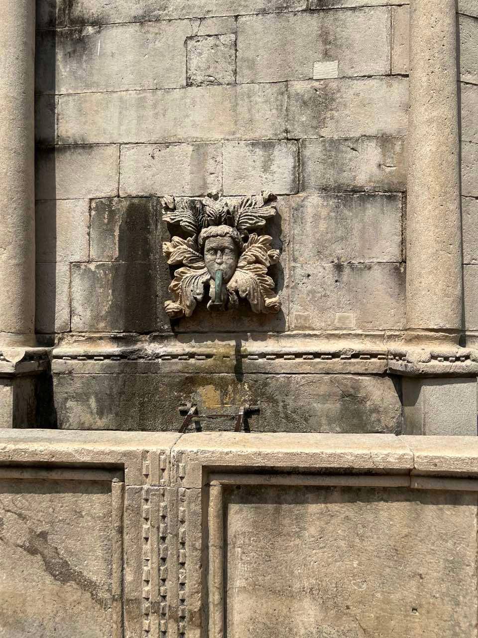 A CLOSE-up of a carved stone mask at the fountain.