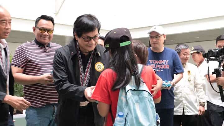 Cabinet Secretary Benjamin Abalos Jr. hands a program package to a beneficiary during the M.I.L.K. Program launch in Los Baños, Laguna.