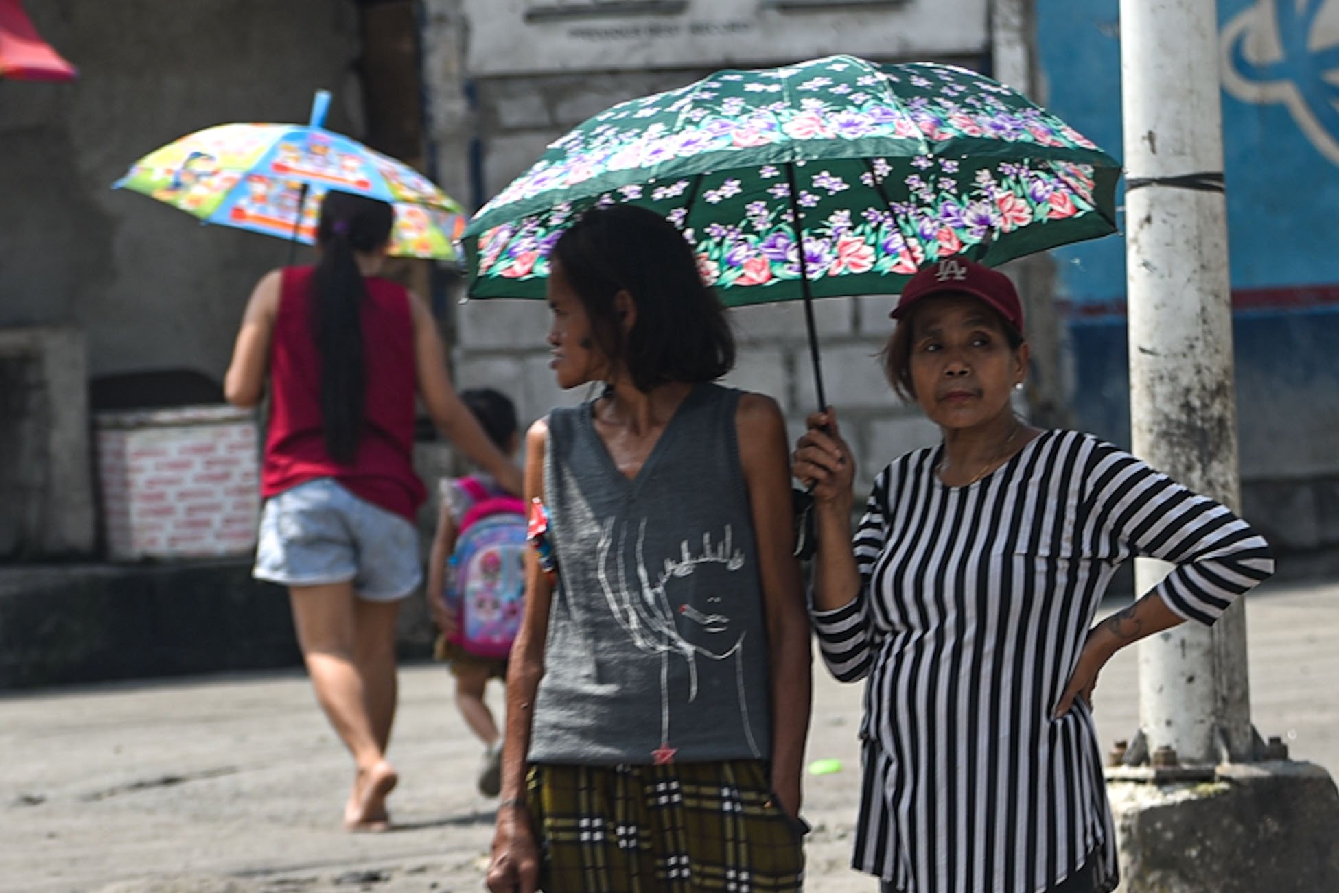 Pedestrians shield themselves from the sun as Habagat season ends