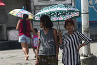 Pedestrians shield themselves from the sun as Habagat season ends