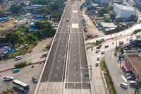 Aerial view of the NLEX-C5 Northlink elevated roadway in Quezon City, showing marked traffic lanes above a busy surface road, with buildings and trees on both sides.