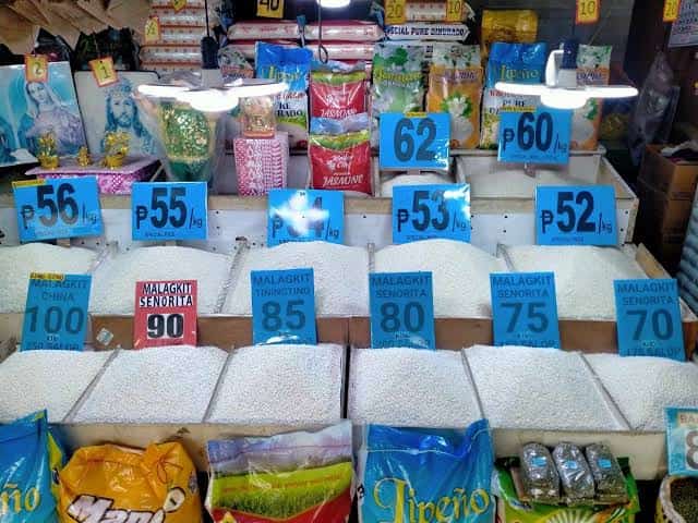 FILE PHOTO — Different varieties of rice are displayed at a market stall, with posted prices ranging from ₱52 to ₱100 per kilogram. Philippine Statistics Authority data show rice inflation among the bottom 30 percent of income households reached 26.3 percent in Lucena City and 25.3 percent in Quezon province in September 2026.