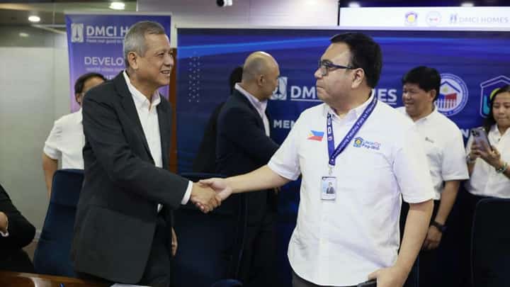 DMCI Homes president Alfredo Austria (left) and Department of Human Settlements and Urban Development Secretary Jose Ramon Aliling shake hands.