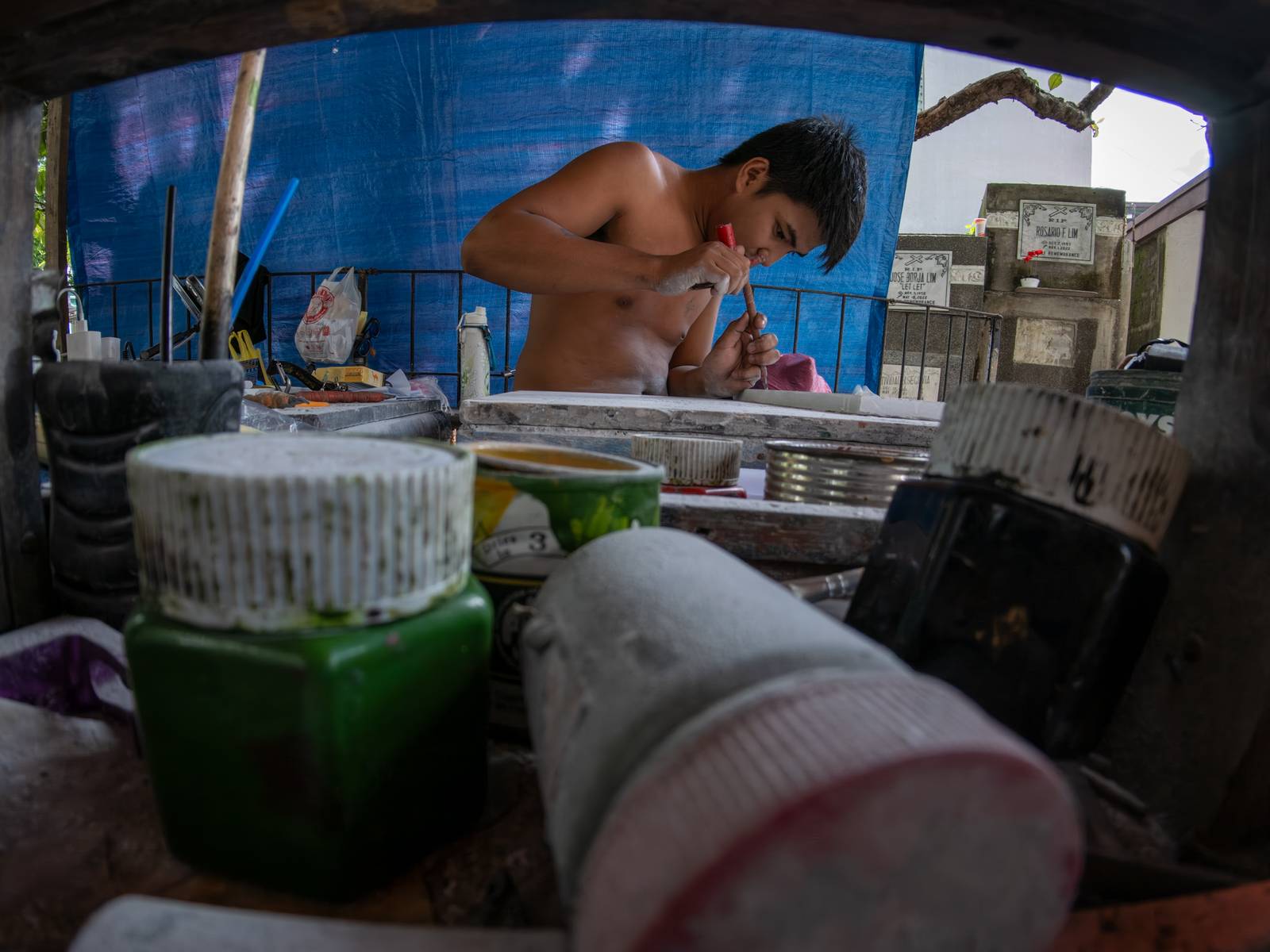 Eugene Gamurot and Cedrick Cayabyab carve a gravestone block at their makeshift workshop in Manila North Cemetery on 17 October 2026. Marble gravemarkers cost ₱500 to ₱5,000, depending on size, while granite markers start at ₱1,500.