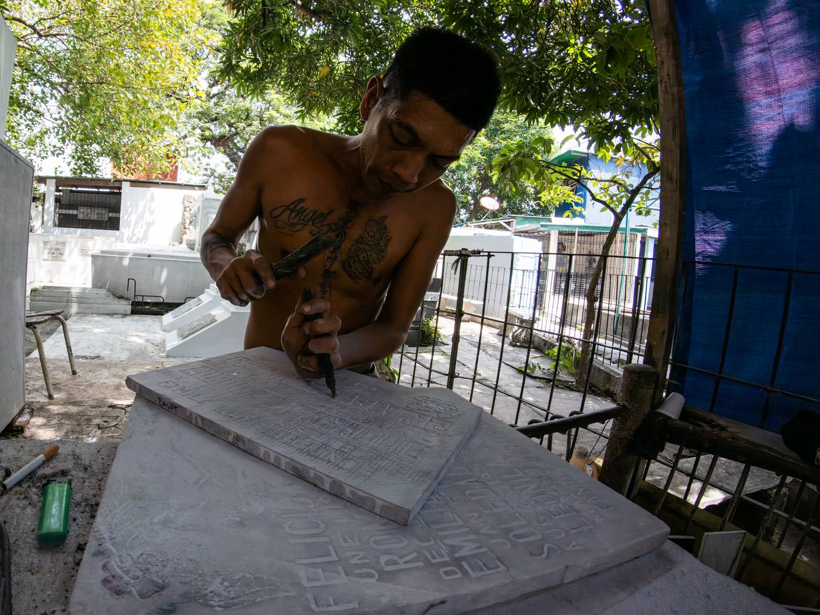 Eugene Gamurot and Cedrick Cayabyab carve a gravestone block at their makeshift workshop in Manila North Cemetery on 17 October 2026. Marble gravemarkers cost ₱500 to ₱5,000, depending on size, while granite markers start at ₱1,500.