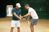 ROLAND Kraut, PCA Open Committee Member and DLSU Tennis Head Coach (right) teaches a member of the press the basics of tennis at a mini-clinic held following the media launch of the 43rd PCA Open, the first iteration the Palawan Group of Companies has served as a major backer.
