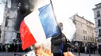 A PROTESTER waves a French flag near a fire during clashes over the rising cost of living in Marseille, France, on 17 October.