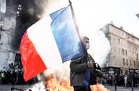 A PROTESTER waves a French flag near a fire during clashes over the rising cost of living in Marseille, France, on 17 October.