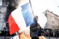 A PROTESTER waves a French flag near a fire during clashes over the rising cost of living in Marseille, France, on 17 October.