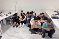 THE alleged fraudsters who were caught during a raid at a suspected scam hub in Subic wait for operatives from the National Bureau of Investigation to finish their inventory of the area.