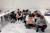 THE alleged fraudsters who were caught during a raid at a suspected scam hub in Subic wait for operatives from the National Bureau of Investigation to finish their inventory of the area.