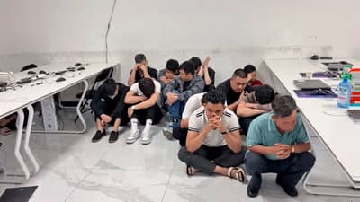 THE alleged fraudsters who were caught during a raid at a suspected scam hub in Subic wait for operatives from the National Bureau of Investigation to finish their inventory of the area.