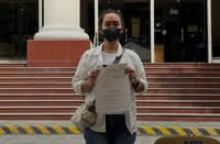 A former staff member of Laguna Board Member Angelica Jones Alarva holds documents outside the Office of the Ombudsman after filing an administrative complaint against the provincial legislator on Friday, 23 October 2026.