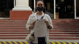 A former staff member of Laguna Board Member Angelica Jones Alarva holds documents outside the Office of the Ombudsman after filing an administrative complaint against the provincial legislator on Friday, 23 October 2026.