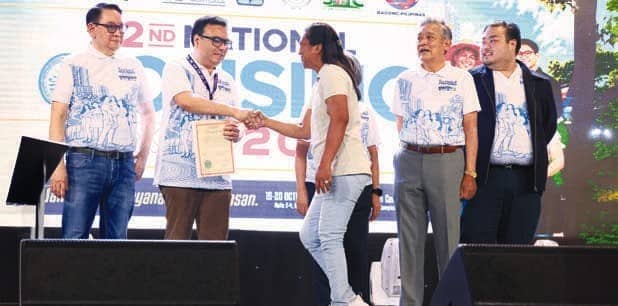 SECRETARY Aliling, SHFC President and CEO Laxa, NHMFC President Tobias, ang NHA General Manager Joeben Tai award a land title to an Expanded 4PH beneficiary during the Expo.