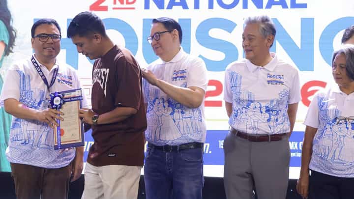 DEPARTMENT of Human Settlements and Urban Development Secretary Jose Ramon Aliling (left) hands over a land title to a beneficiary — one of five members of the Kapisanan sa Landas ng Paninirahan Inc. — under the Social Housing Finance Corporation’s Community Mortgage Program — one of the SHFC’s flagship program under the Marcos administration’s Expanded Pambansang Pabahay para sa Pilipino Program during the 2nd National Housing Expo at SMX Convention Center on 19 October 2026. With Secretary Aliling are (from left) SHFC president and CEO Federico Laxa, National Home Mortgage Finance Corporation president Renato Tobias, and Pag-IBIG Fund chief executive officer Marilene Acosta.