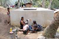 A MOTHER washes clothes while her children take a bath at a communal tap outside their house in Barangay Datal Anggas in Alabel, Sarangani.