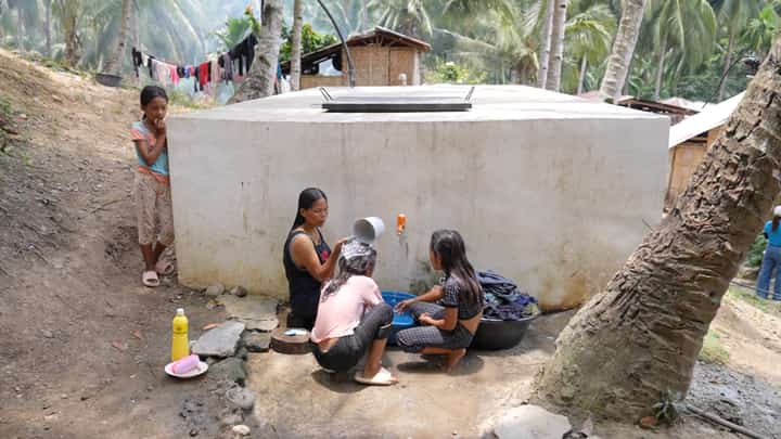 A MOTHER washes clothes while her children take a bath at a communal tap outside their house in Barangay Datal Anggas in Alabel, Sarangani.