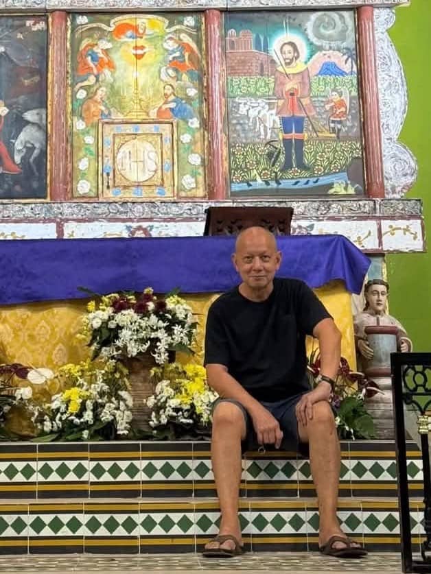 ARTIST-RESTORER Guy Custodio sits before the painted retablo he created.