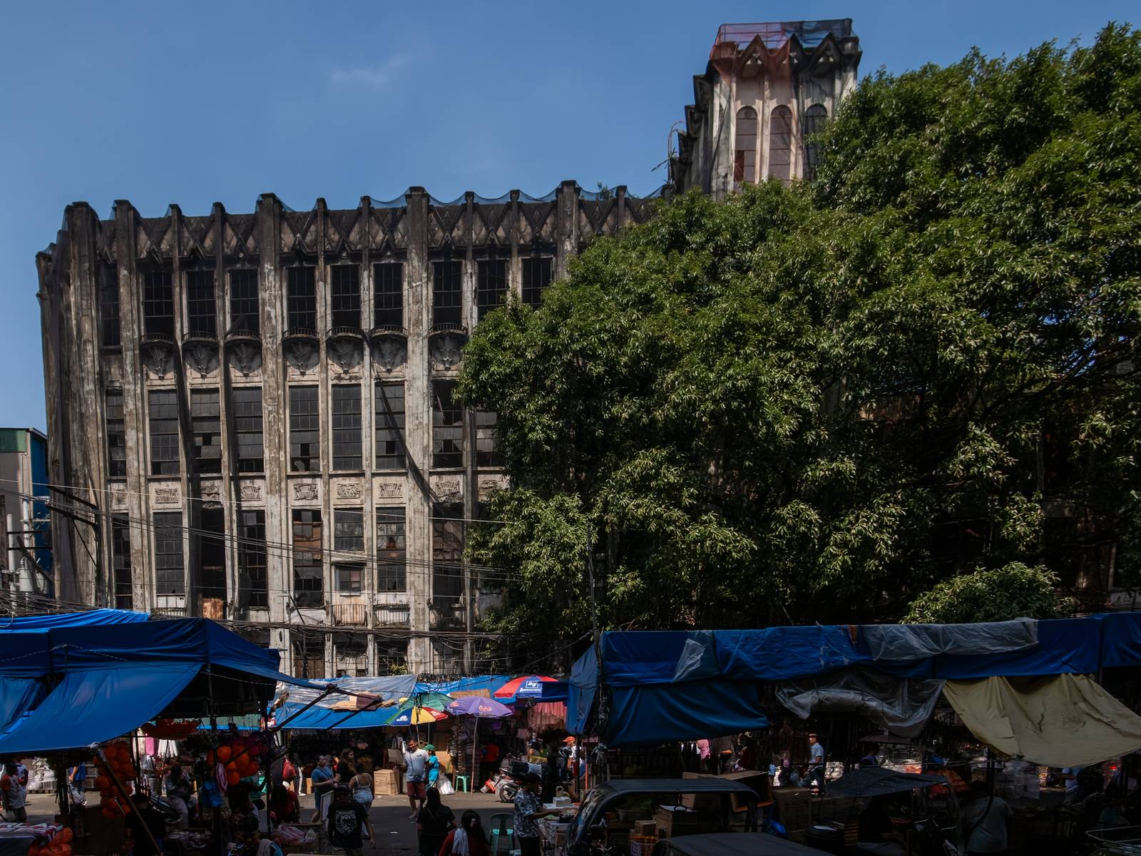 Protective nets cover the pre-war Art Deco IDES O’Racca Building in Divisoria, Manila, to shield vendors, shoppers and pedestrians from falling debris in this photo taken on 26 October 2026. Declared a cultural property by the National Museum of the Philippines, the building reportedly faces demolition despite calls for its preservation by heritage groups.