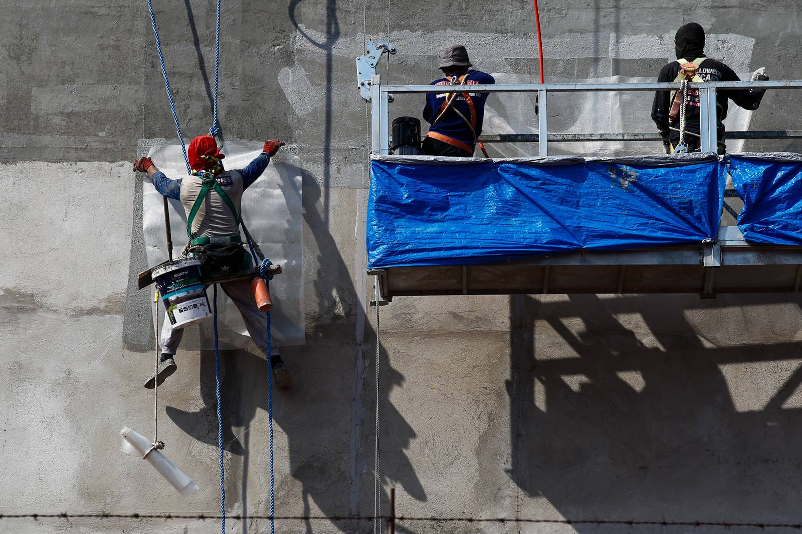 High-rise workers apply waterproofing to a building in Manila on 26 October 2026, as the Department of Labor and Employment clarifies compensation coverage for heat-related illnesses under the Employees’ Compensation Program amid the “super” El Niño and extreme heat.