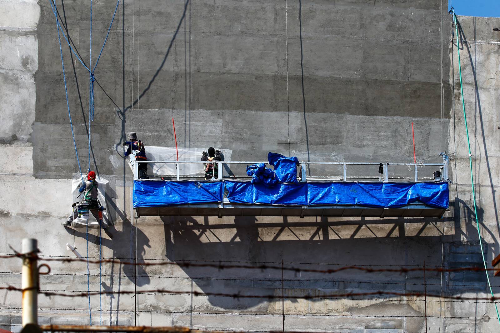 High-rise workers apply waterproofing to a building in Manila on 26 October 2026, as the Department of Labor and Employment clarifies compensation coverage for heat-related illnesses under the Employees’ Compensation Program amid the “super” El Niño and extreme heat.