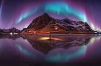 HIS winning photograph, The Emerald Arch Over Lofoten, Norway, captures the Northern Lights forming a sweeping arch above a mountain and reflecting across the water.