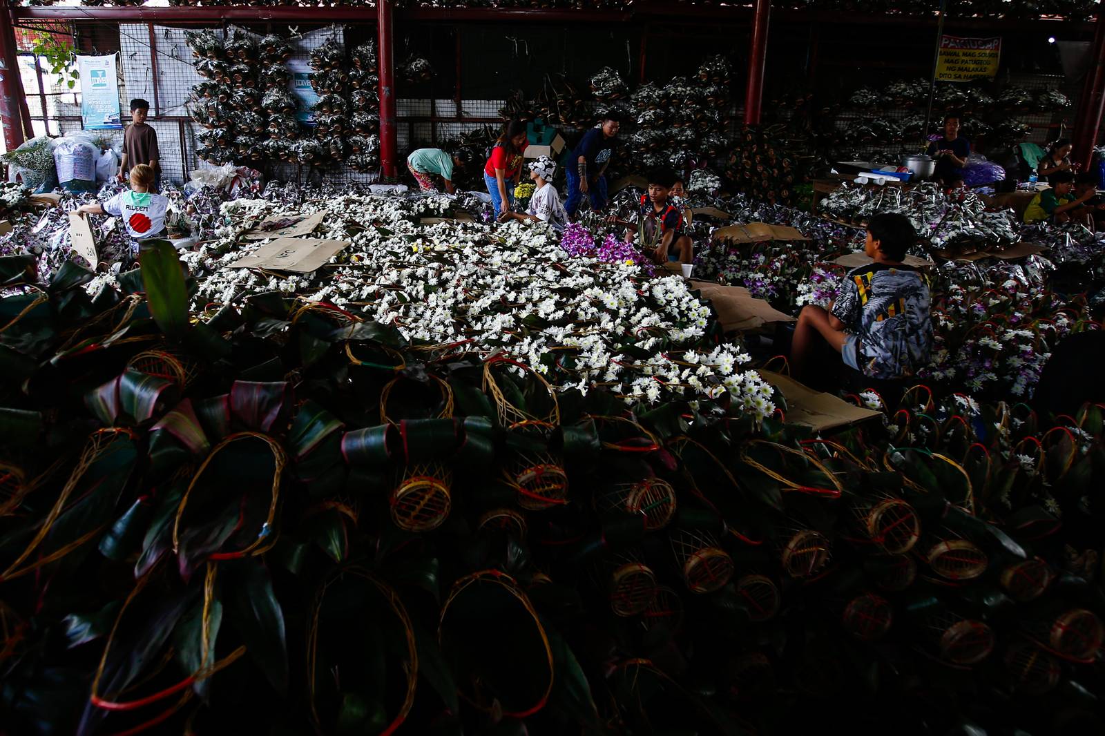 Workers assemble flower baskets at a shop in Dangwa, Manila on 29 October 2026, ahead of Undas. Each basket sells for 200 pesos, with prices expected to rise as the observance draws near.