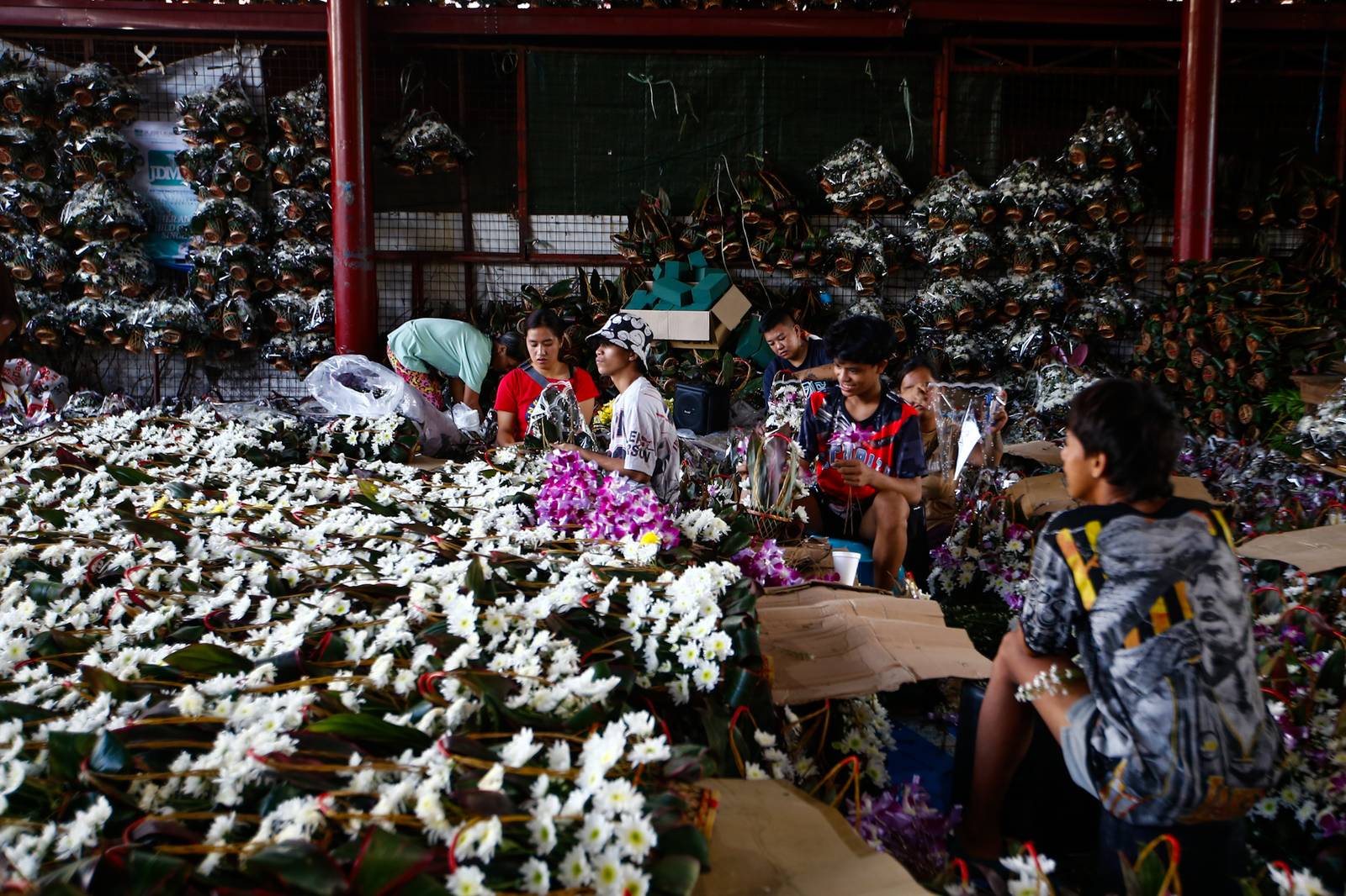 Workers assemble flower baskets at a shop in Dangwa, Manila on 29 October 2026, ahead of Undas. Each basket sells for 200 pesos, with prices expected to rise as the observance draws near.