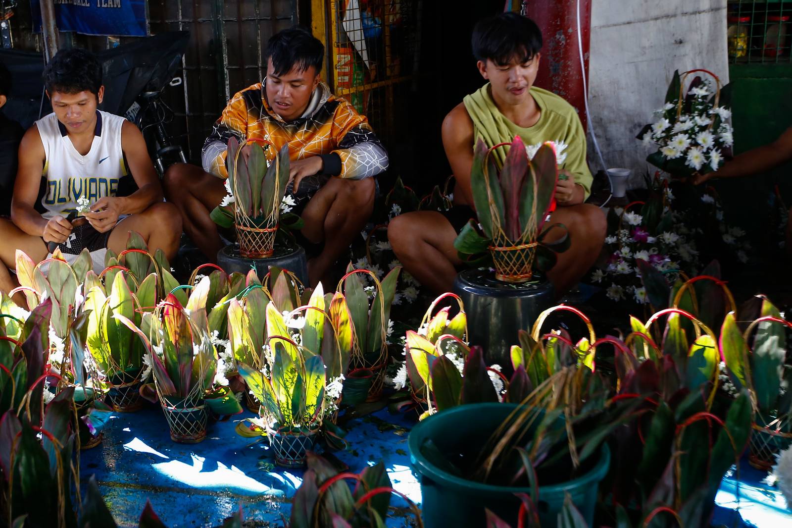 Workers assemble flower baskets at a shop in Dangwa, Manila on 29 October 2026, ahead of Undas. Each basket sells for 200 pesos, with prices expected to rise as the observance draws near.