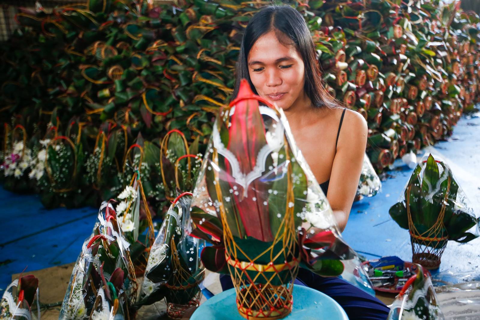 Workers assemble flower baskets at a shop in Dangwa, Manila on 29 October 2026, ahead of Undas. Each basket sells for 200 pesos, with prices expected to rise as the observance draws near.