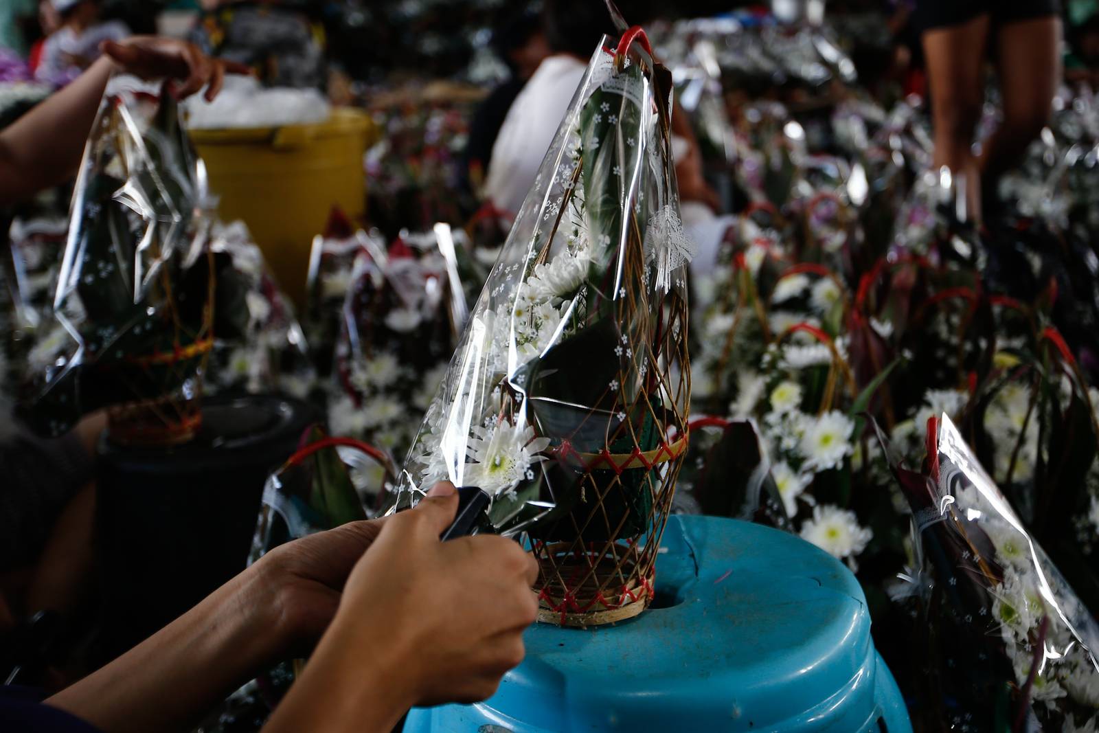 Workers assemble flower baskets at a shop in Dangwa, Manila on 29 October 2026, ahead of Undas. Each basket sells for 200 pesos, with prices expected to rise as the observance draws near.