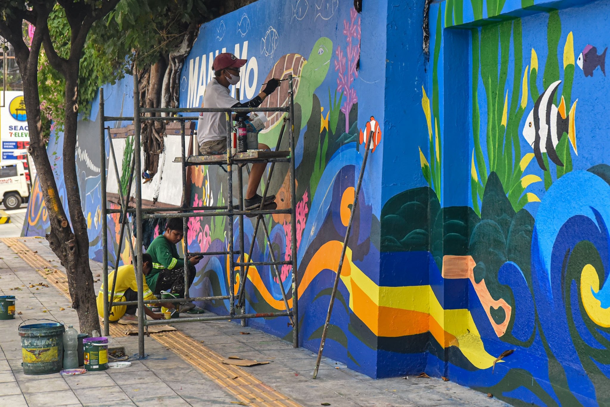 Workers paint mural along EDSA