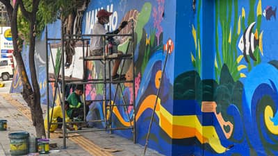 Workers paint mural along EDSA