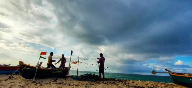 மீன்பிடி வலையை சரி செய்யும் மீனவர்கள்